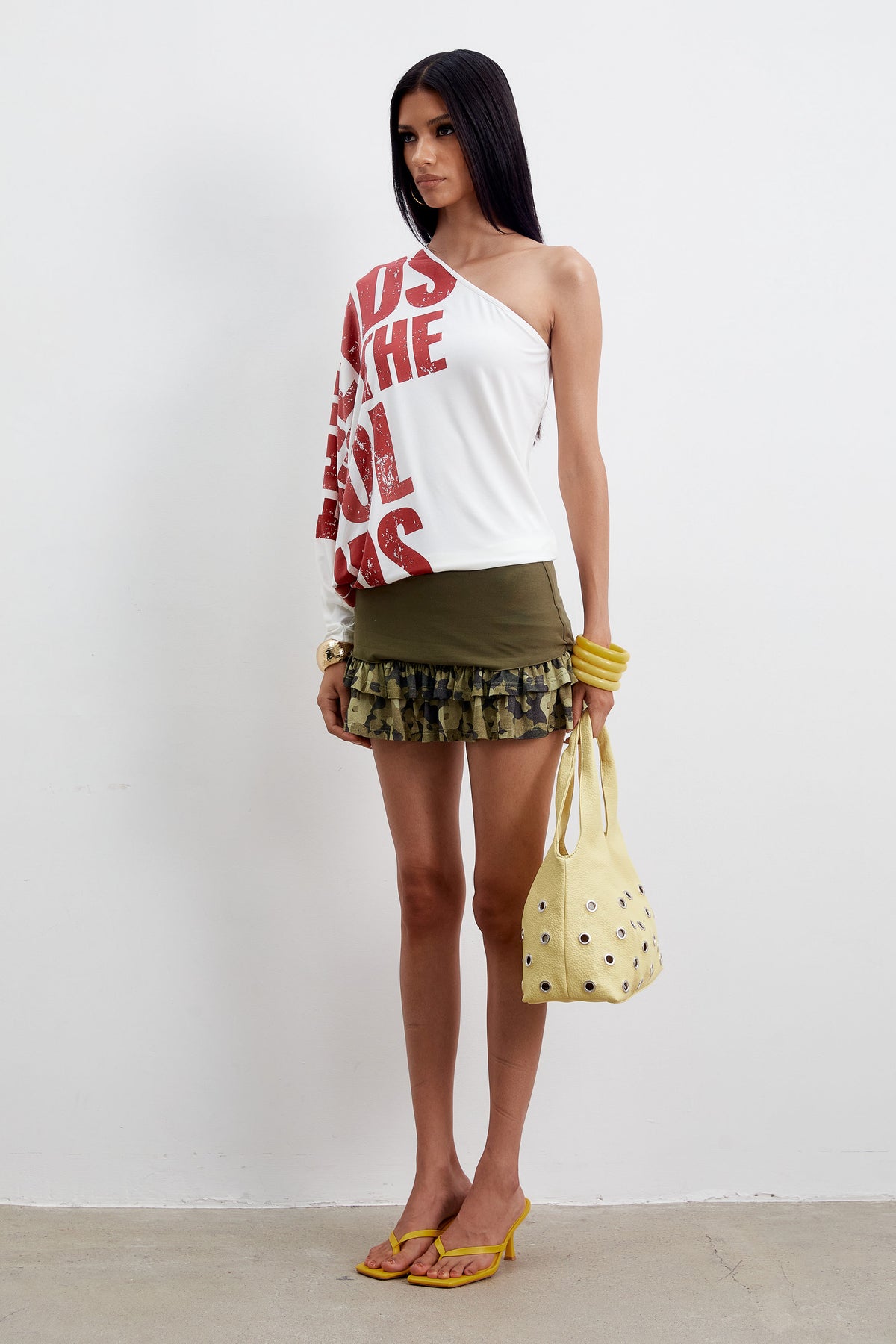 Side view of the Eli Top, a white one-shoulder draped jersey top